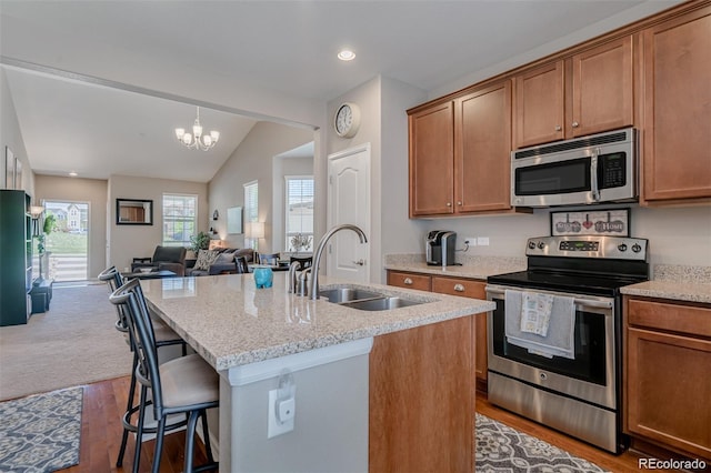 kitchen featuring open floor plan, appliances with stainless steel finishes, a sink, and a kitchen island with sink