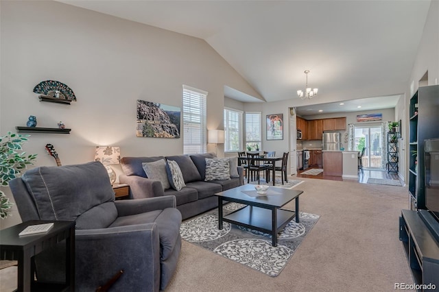 living room with a notable chandelier, high vaulted ceiling, and light colored carpet