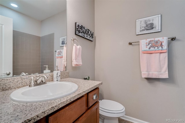 bathroom featuring toilet, baseboards, and vanity