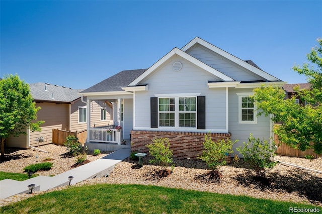 view of front of property featuring a porch, fence, and brick siding