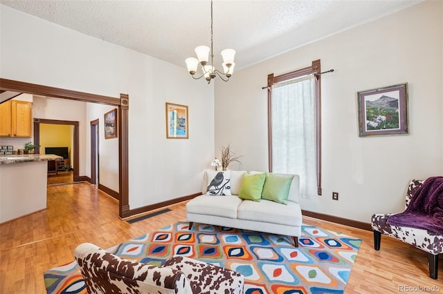 2119 W Pikes Peak Ave, Colorado Springs, CO 80904 - living area featuring light wood-style flooring, a chandelier, a textured ceiling, and baseboards