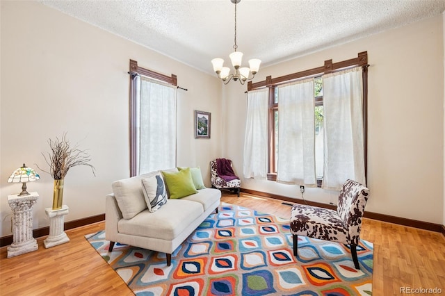2119 W Pikes Peak Ave, Colorado Springs, CO 80904 - living room featuring a textured ceiling, a chandelier, light wood-style floors, and baseboards