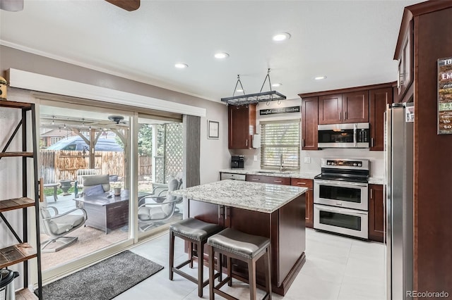 8101 S San Juan Range Rd, Littleton, CO 80127 - kitchen with appliances with stainless steel finishes, a sink, a kitchen island, light stone counters, and a breakfast bar