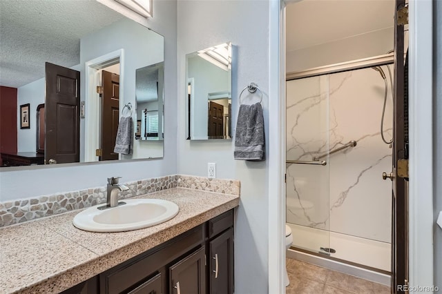 8101 S San Juan Range Rd, Littleton, CO 80127 - bathroom with a marble finish shower, vanity, a textured ceiling, toilet, and tile patterned floors