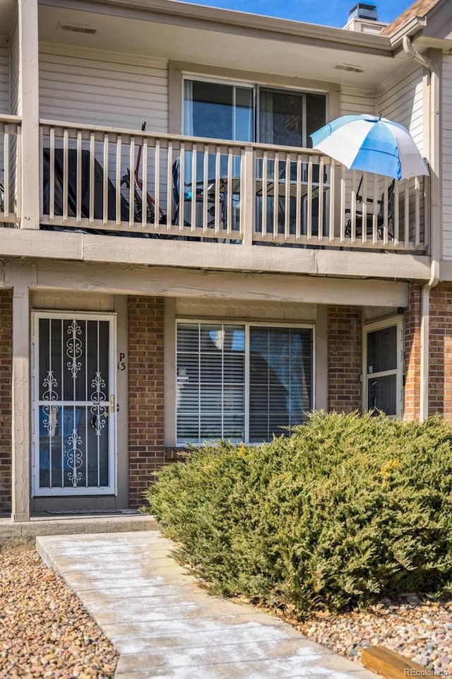 entrance to property featuring a balcony and brick siding