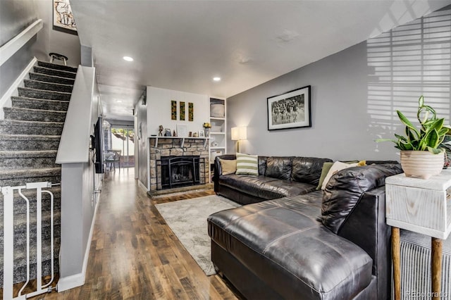 living area with recessed lighting, stairs, dark wood-style flooring, and a stone fireplace