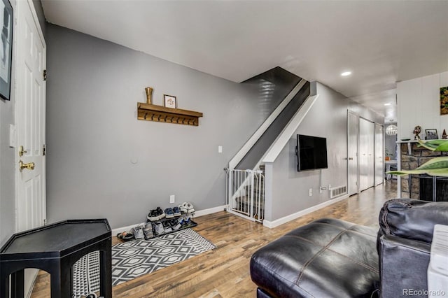 living room with stairs, wood finished floors, visible vents, and baseboards