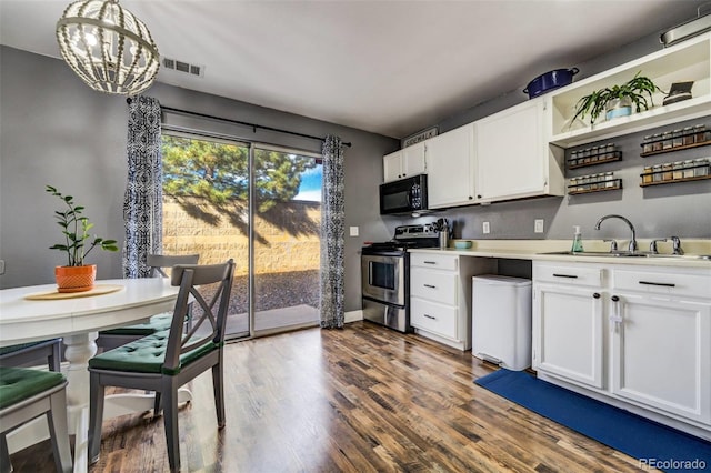 kitchen with black microwave, a sink, light countertops, stainless steel electric range, and pendant lighting