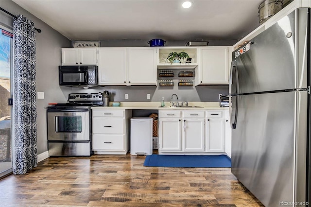 kitchen with open shelves, stainless steel appliances, light countertops, white cabinetry, and a sink