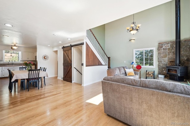 32392 Lodgepole Dr, Evergreen, CO 80439 - living room with a barn door, a wood stove, light wood finished floors, recessed lighting, and a chandelier