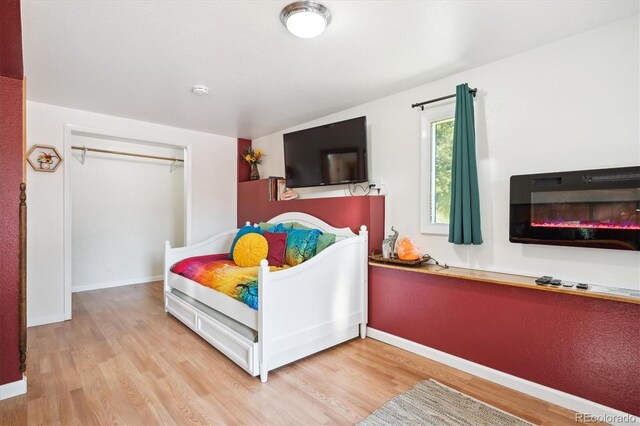 32392 Lodgepole Dr, Evergreen, CO 80439 - bedroom with light wood-style flooring, lofted ceiling, and a glass covered fireplace
