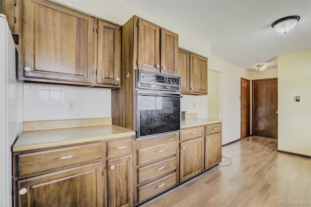 65 Yeoman Ln, Divide, CO 80814 - kitchen with black oven, light wood-style floors, light countertops, backsplash, and brown cabinetry