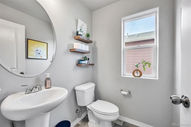 bathroom with toilet, baseboards, and a sink