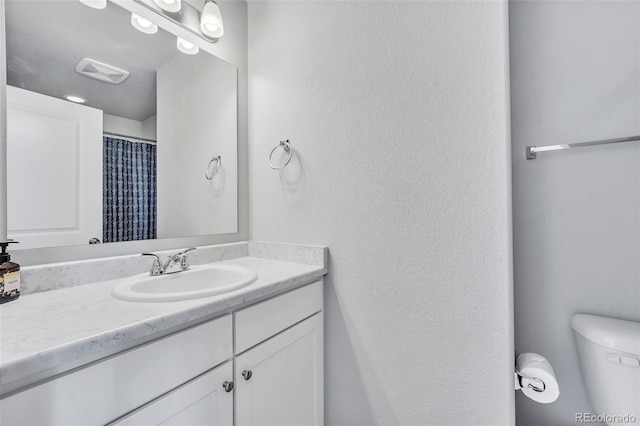 bathroom featuring visible vents, toilet, and vanity