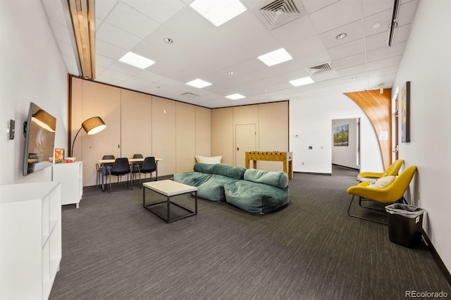 living area featuring a drop ceiling, visible vents, baseboards, and carpet flooring