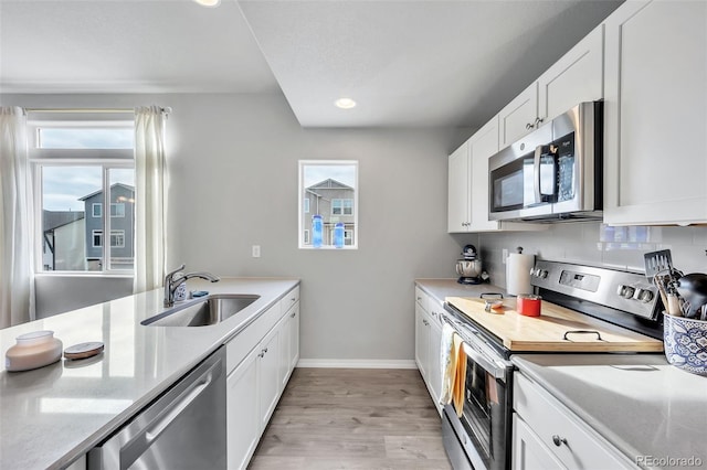 kitchen with a sink, stainless steel appliances, a healthy amount of sunlight, and white cabinetry