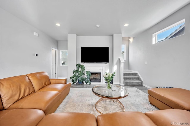 living room featuring wood finished floors, baseboards, recessed lighting, stairs, and a glass covered fireplace