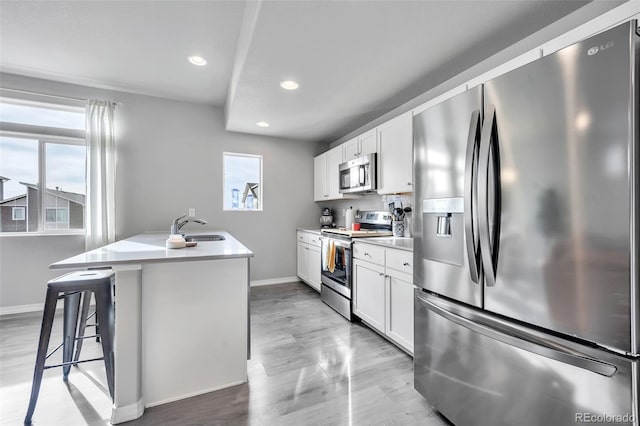 kitchen with a wealth of natural light, white cabinets, appliances with stainless steel finishes, and a sink