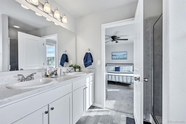 ensuite bathroom with double vanity, connected bathroom, ceiling fan, and a sink