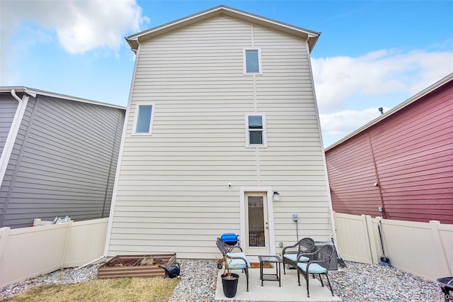 rear view of property with a patio area, a fenced backyard, and a vegetable garden