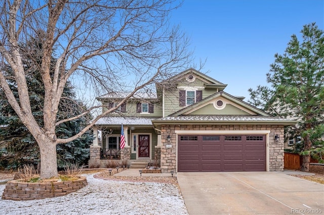 view of front facade with an attached garage, driveway, a porch, and stone siding