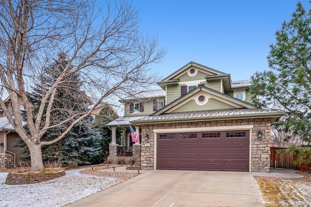 view of front of house featuring a garage, stone siding, driveway, and fence