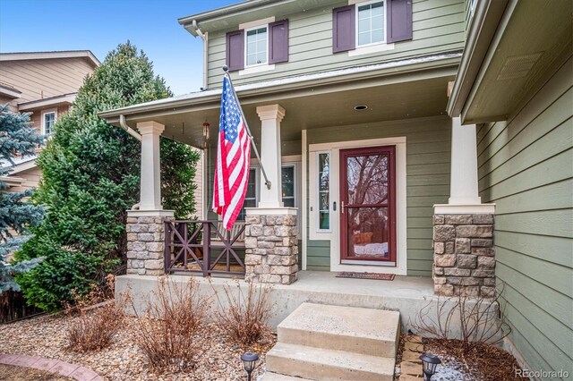 property entrance featuring covered porch and stone siding