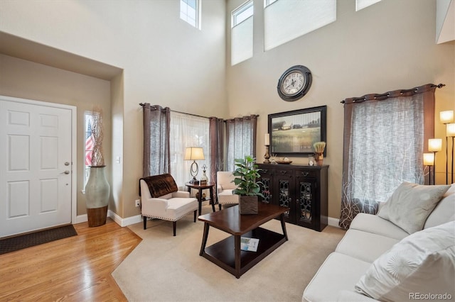 living area featuring baseboards, a high ceiling, wood finished floors, and a healthy amount of sunlight