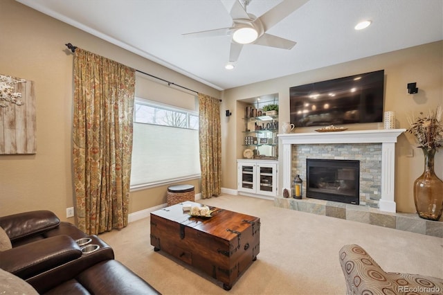 living room with carpet, a fireplace, a ceiling fan, and baseboards