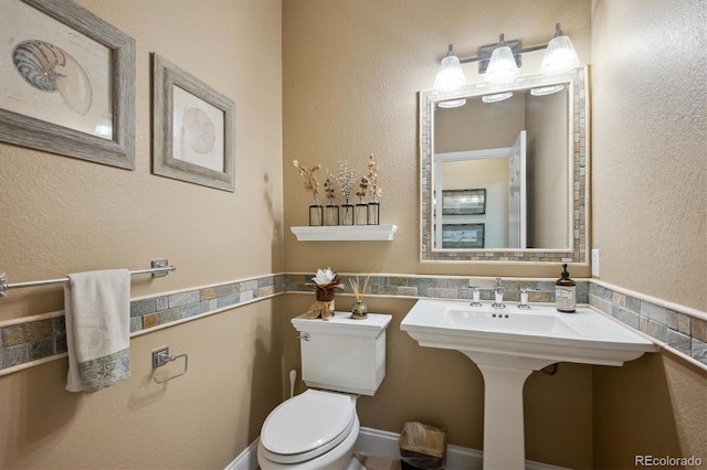 bathroom with a textured wall and toilet