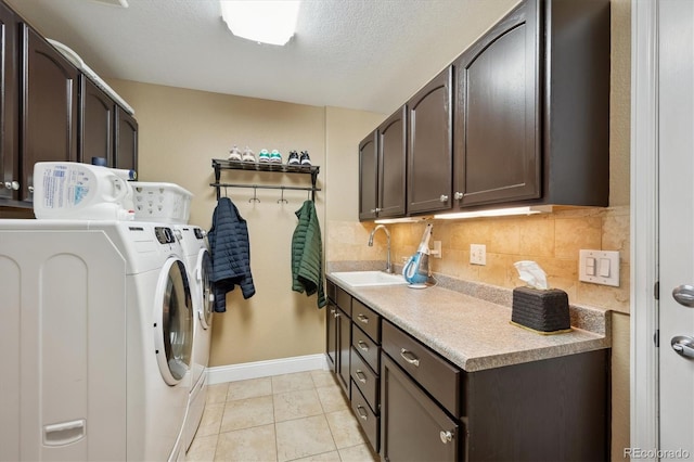 laundry area with light tile patterned floors, a textured ceiling, a sink, cabinet space, and washer and clothes dryer