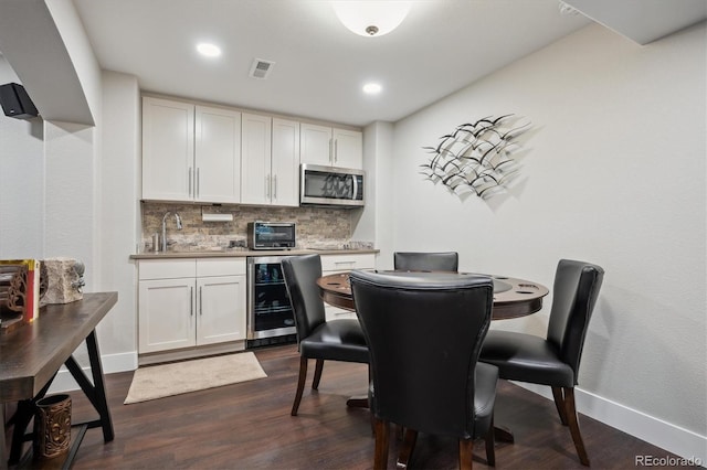 dining space featuring dark wood-style floors, a toaster, visible vents, beverage cooler, and baseboards