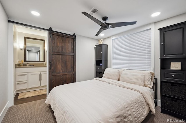 bedroom with a barn door, visible vents, ensuite bathroom, and recessed lighting