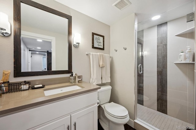 bathroom featuring toilet, a stall shower, visible vents, and vanity