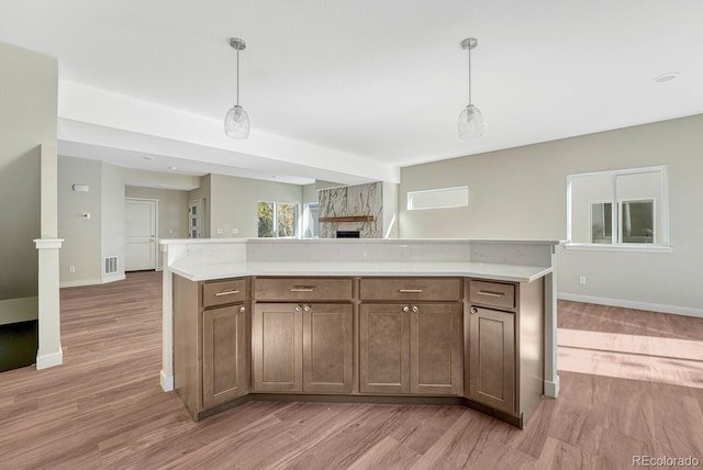 kitchen with light hardwood / wood-style flooring, decorative light fixtures, and a fireplace