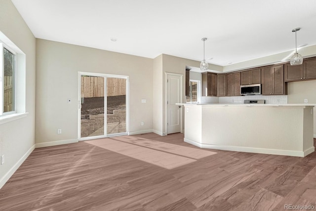 kitchen with light hardwood / wood-style flooring, dark brown cabinetry, and decorative light fixtures