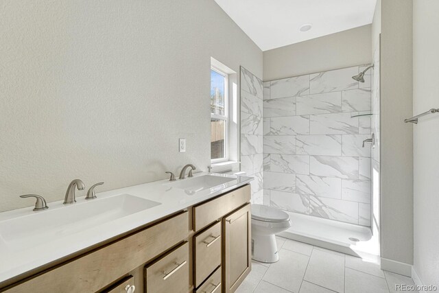 bathroom with vanity, tiled shower, toilet, and tile patterned flooring