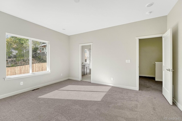 unfurnished bedroom featuring connected bathroom and light carpet