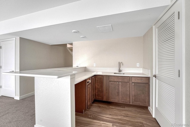 kitchen featuring a kitchen breakfast bar, kitchen peninsula, hardwood / wood-style floors, and sink