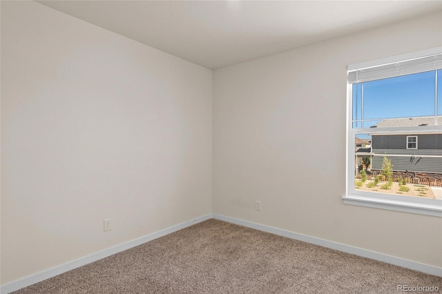 carpeted spare room featuring baseboards