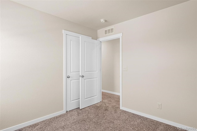 unfurnished bedroom featuring baseboards, visible vents, and light colored carpet