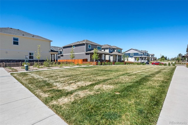 view of front facade featuring a front lawn, fence, and a residential view