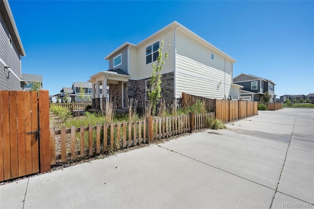 view of side of property featuring a residential view, stone siding, and fence