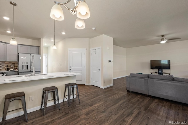 kitchen featuring stainless steel fridge with ice dispenser, a breakfast bar, decorative light fixtures, light countertops, and gray cabinetry