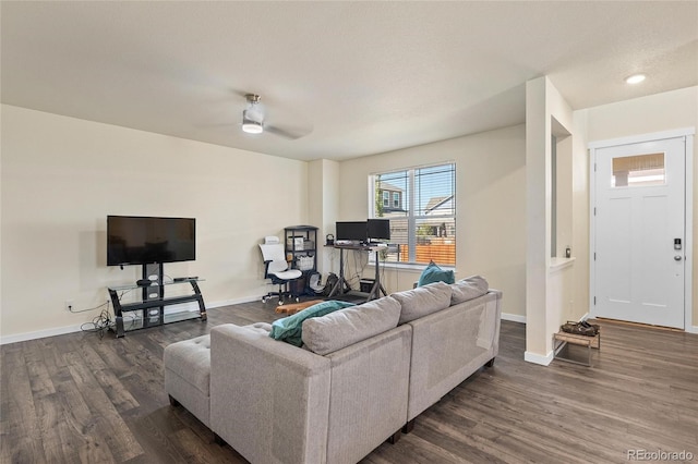 living area with ceiling fan, baseboards, and dark wood-type flooring