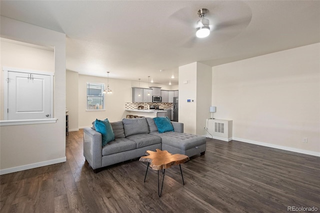 living room with dark wood-style floors, ceiling fan, and baseboards