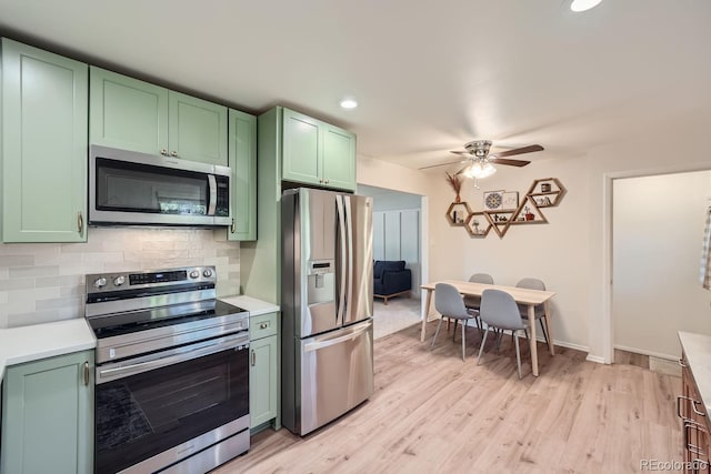 kitchen featuring tasteful backsplash, light wood-type flooring, stainless steel appliances, and green cabinets