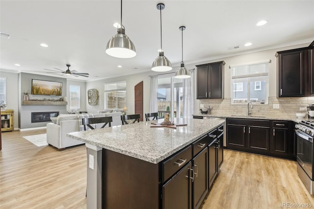 kitchen with stainless steel stove, decorative light fixtures, a center island, dark brown cabinetry, and light wood-type flooring