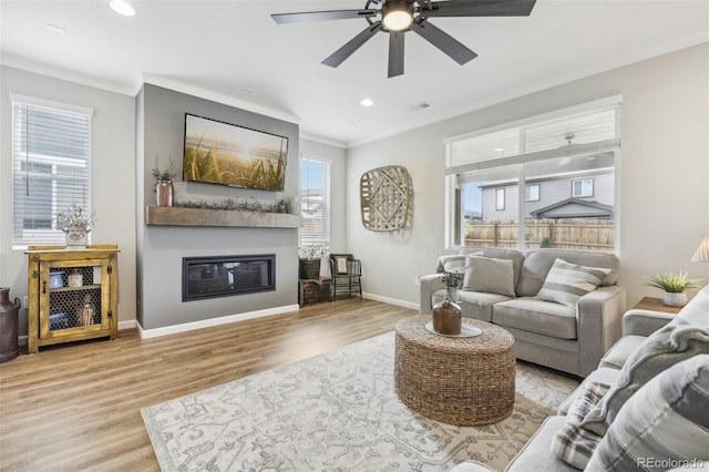 living room featuring ceiling fan, ornamental molding, and light hardwood / wood-style floors