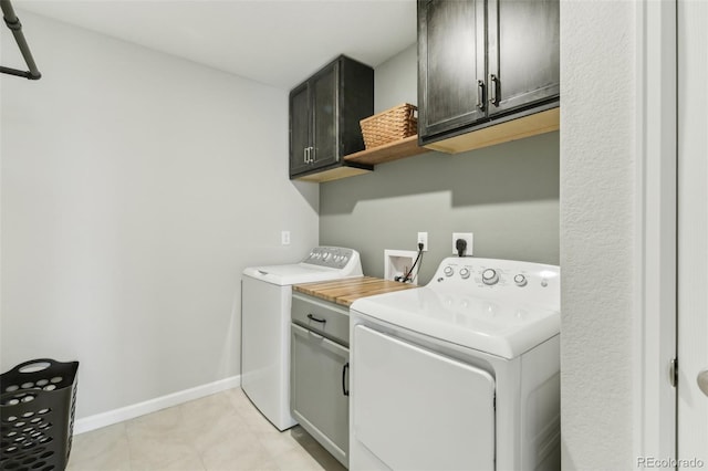 laundry area featuring washer and dryer, cabinet space, baseboards, and light tile patterned floors